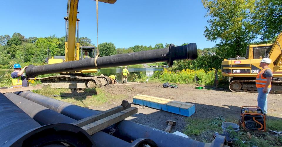 Piece of 12-inch ball and socket pipe on its way from supply pile to assembly.